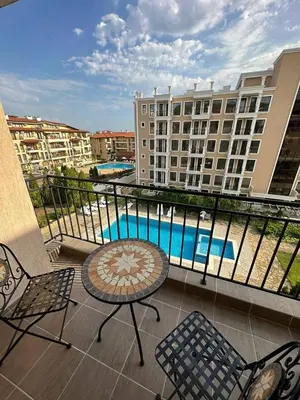 a balcony with a table and chairs and a pool at Sveti Vlas, Rodopi Bay Apartment in Sveti Vlas