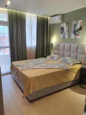 a bed in a bedroom with a large window at Divalla Apartment Burgas in Burgas City