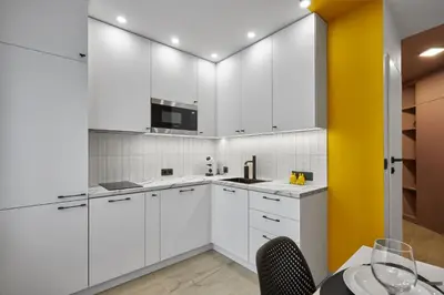 a kitchen with white cabinets and a yellow wall at Sea Moreto Apartment 3 in Burgas City