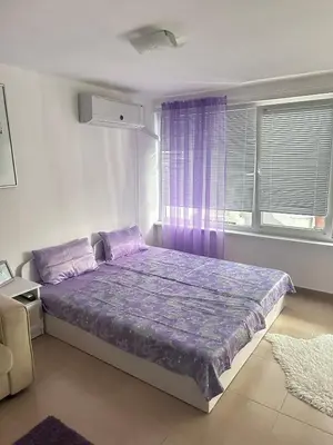 a bedroom with a bed with purple sheets and a window at House Velevi in Sveti Vlas