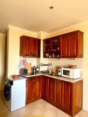 a kitchen with wooden cabinets and a white microwave at Amara Holiday Santa Marina, Sozopol in Sozopol