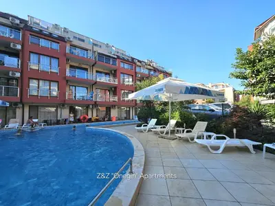 a swimming pool with chairs and an umbrella and a building at Z&Z 