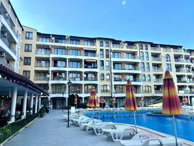 a large building with a pool and chairs and umbrellas at Royal Dreams Apartments, Sunny Beach in Sunny Beach