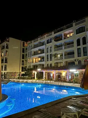 a large swimming pool in front of a building at night at Royal Dreams Apartments, Sunny Beach in Sunny Beach