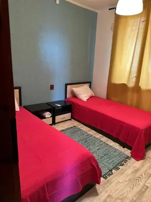a room with two beds with red sheets and a table at Villa Nikoleta in Sveti Vlas
