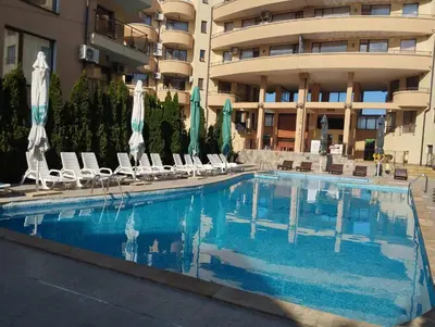 a swimming pool with chairs and umbrellas in front of a building at Quiet 1-Bed Flat in Antonia Complex by Flat Mаnager in Sveti Vlas