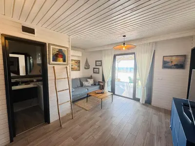 a living room with a blue couch and a tv at Camping Gardenia - Bungalow SeaBed in Lozenets