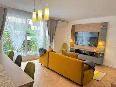 a living room with a yellow couch and a tv at Apartament A 2BD in Burgas City