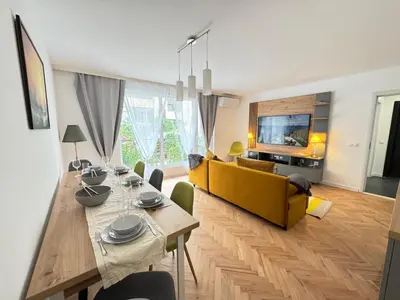 a living room with a table and a yellow couch at Apartament A 2BD in Burgas City
