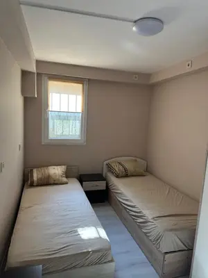 two beds in a small room with a window at Rumen Apartment in Nesebar
