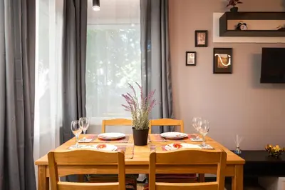 a dining room table with chairs and a wooden table with wine glasses at Top Central Flats with Style in Varna City