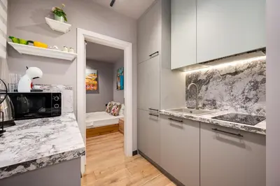 a kitchen with white cabinets and marble counter tops at Top Central Flats with Style in Varna City