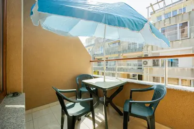 a table with chairs and an umbrella on a balcony at Marea 1 in Pomorie