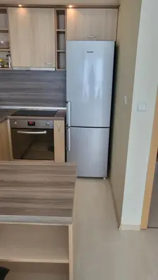 a white refrigerator in a kitchen with wooden cabinets at Делукс апартамент -Тюркоазен релакс in Pomorie