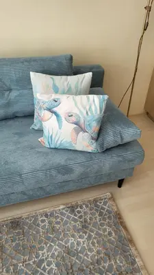 a blue couch with two pillows on it at Делукс апартамент -Тюркоазен релакс in Pomorie