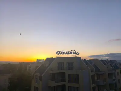 a building with a sign on top of it at sunset at Golden Hermes, Studio z basenem in Sunny Beach