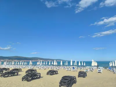 a beach with chairs and umbrellas and the ocean at Golden Hermes, Studio z basenem in Sunny Beach