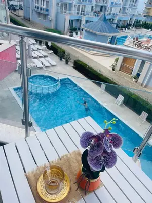 a vase of flowers sitting on a table next to a pool at Rose Garden Apartment 10 in Sunny Beach