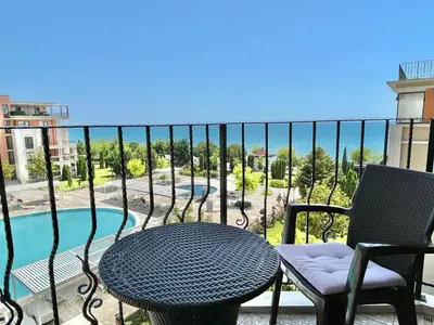 a table and chairs on a balcony with a swimming pool at Prestige Fort Aparthotel - Private apartment - BSR - 3 in Sveti Vlas