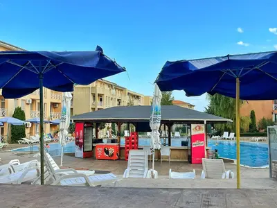 a group of chairs and umbrellas next to a pool at Chocolate Apartment on Sunny Day 6 Complex in Tŭnkovo