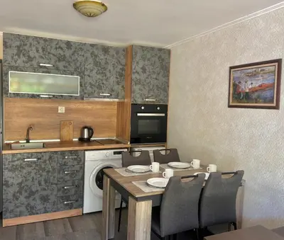 a kitchen with a table and a sink and a dishwasher at Иглика Апарт Несебър in Nesebar
