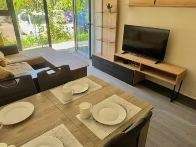 a living room with a television and a table and chairs at Иглика Апарт Несебър in Nesebar