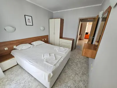 a bedroom with a white bed and a mirror at Тристаен просторен апартамент с две отделни спални in Sunny Beach