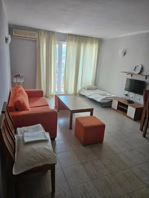 a living room with a couch and a table at Тристаен просторен апартамент с две отделни спални in Sunny Beach