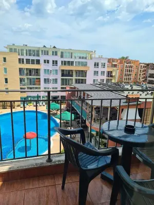 a balcony with a pool and tables and chairs at Тристаен просторен апартамент с две отделни спални in Sunny Beach