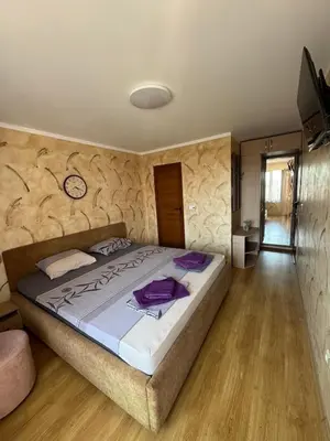 a bedroom with a large bed with a clock on the wall at Guest House Amfora with a sea view in Sozopol