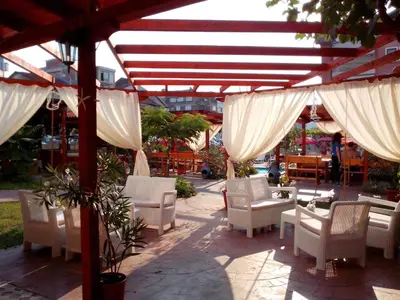 a patio with white chairs and white curtains at Apartment Terrace under the stars in Primorsko