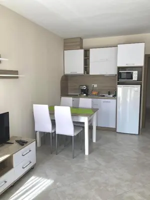 a kitchen with a table and white chairs in it at Apartments in Villas Apolon in Sozopol