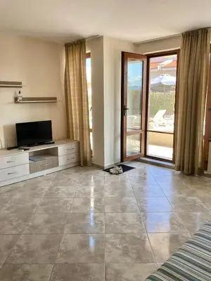 a large living room with a television and a balcony at Apartments in Villas Apolon in Sozopol