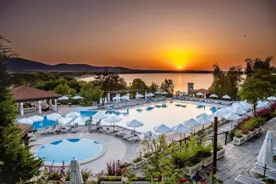 a resort with a pool with a sunset in the background at Marena Studio - Santa Marina, Sozopol in Sozopol