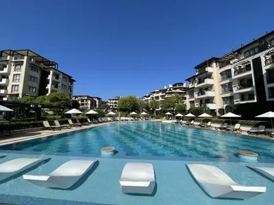 a large swimming pool with lounge chairs and buildings at Oasis Beach Club - 