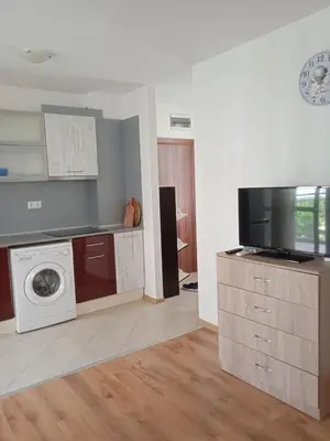 a kitchen with a washing machine and a tv at Тристаен апартамент в Бяла комплекс Атлантик in Byala