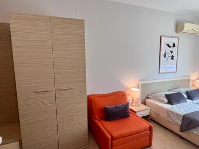 a bedroom with a bed and a orange chair at Apartament Royal Sun Romantic - 5 min to the beach in Sunny Beach