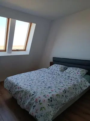 a bedroom with a bed with a floral comforter and two windows at 2 Zimmerwohnung in Shkorpilovtsi