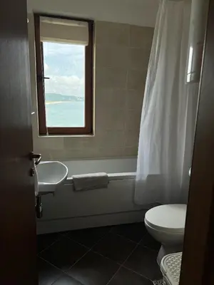 a bathroom with a toilet and a sink and a window at Saint Thomas Holiday Village Condo in Sozopol