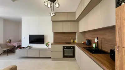 a kitchen with white cabinets and a tv in it at Emperium 1 Apartments Sveti Vlas in Sveti Vlas