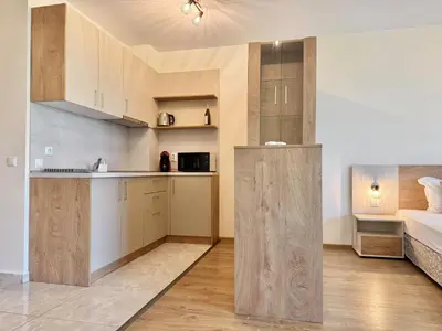 a kitchen with wooden cabinets and a bed in a room at Sea View Allure Studio with Balcony in Primorsko