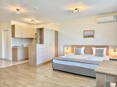 a bedroom with a large bed and a kitchen at Sea View Allure Studio with Balcony in Primorsko