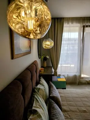 a living room with a couch and a gold chandelier at Ika Apartment Central in Burgas City