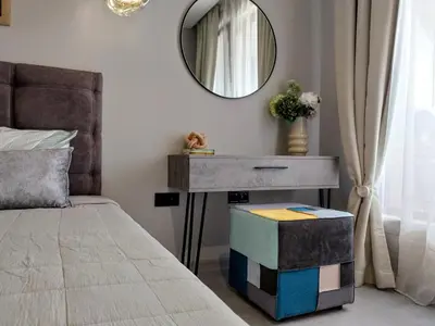 a bedroom with a bed and a table with a mirror at Ika Apartment Central in Burgas City