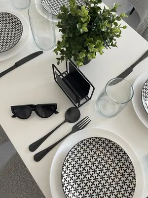a white table with black and white plates and glasses at Marea Garden Apartment Ravda in Ravda