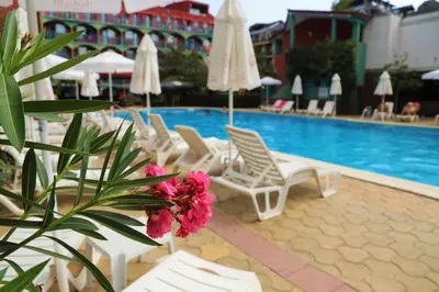 a pool with chairs and umbrellas and a plant with flowers at Jasmine - Menada Apartments in Sunny Beach
