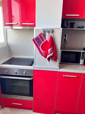 a small kitchen with red cabinets and a microwave at PanoramaView Lazur in Burgas City