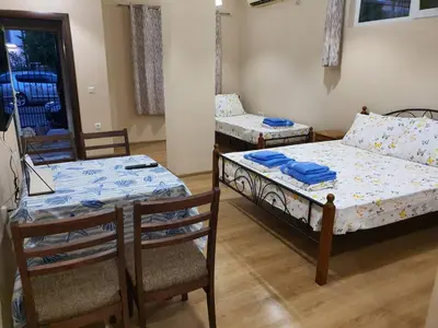 a room with two beds and a table and chairs at Студио Морски бриз in Pomorie