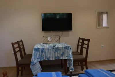 a table with two chairs and a television on a wall at Студио Морски бриз in Pomorie