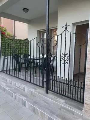 a wrought iron fence with tables and chairs on a porch at Студио Морски бриз in Pomorie